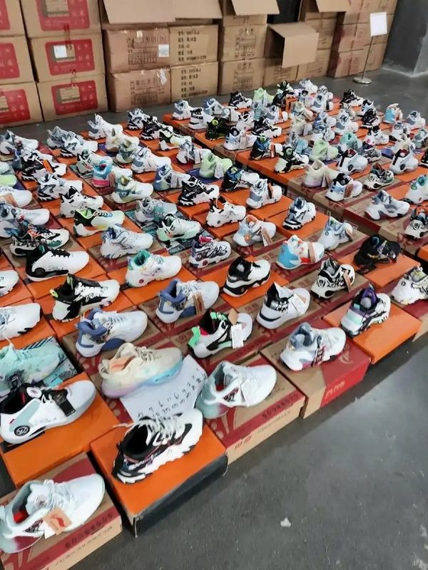 Inventory warehouse — assorted sneaker pairs displayed on shoe boxes ready for QC photography